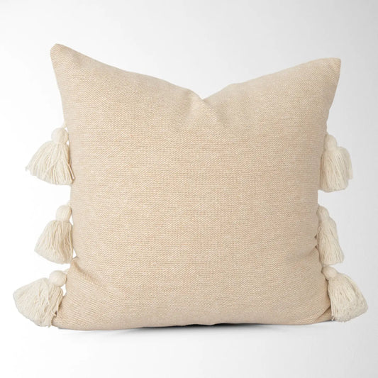 Close-up of a textured pillow cover with side tassels in natural tone.