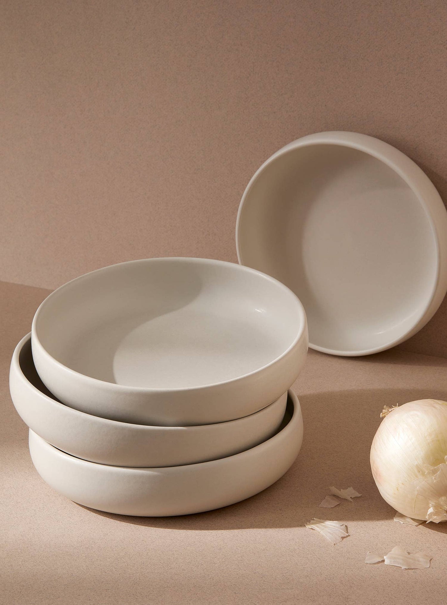 A stack of Minimalist stoneware pasta plate in a modern white finish